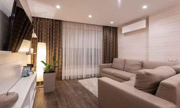 Warm cozy living room with neutral seating, layered textiles, wood accents, and soft natural light.